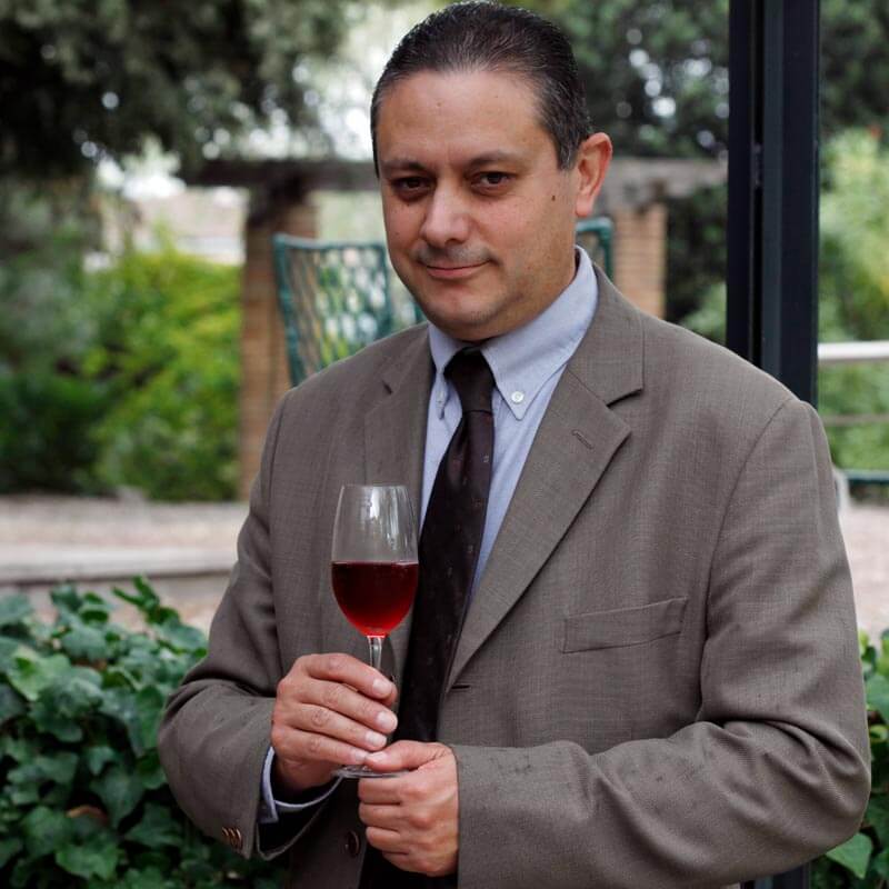 Pedro Muñoz Gómez, Technical Director and Winemaker outside the winery, dressed in business suit, holding a glass of Cava