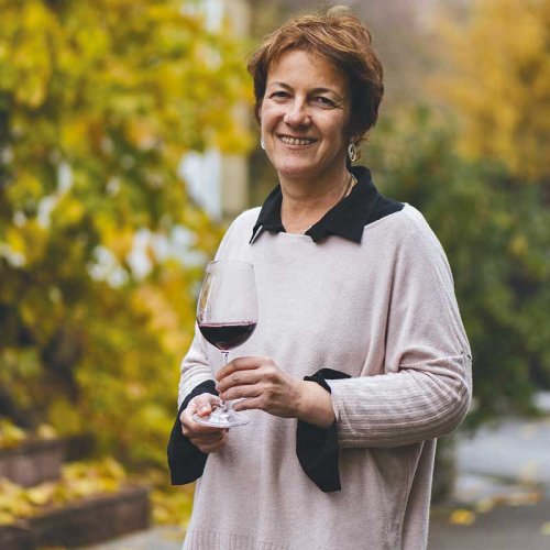 Marria Larrea, Technical Director of the CVNE group and Chief Winemaker of Monopole, Cune and Imperial wines, standing outside among autumn leaves, holding a glass of red wine