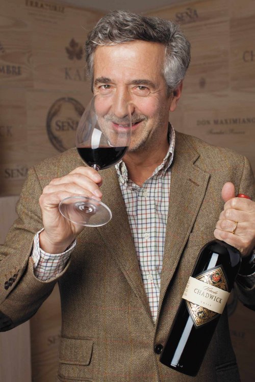 Eduardo Chadwick, President and Owner, portrait image, holding a bottle of Viñedo Chadwick in one hand, and taking a deep breath of the wine in the glass in the other hand