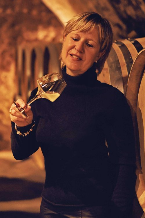 Catherine Corbeau-Mellot, stands in the yellow light of the barrel cellar, and examines a white wine glass tilted to see the colour of the fermenting wine