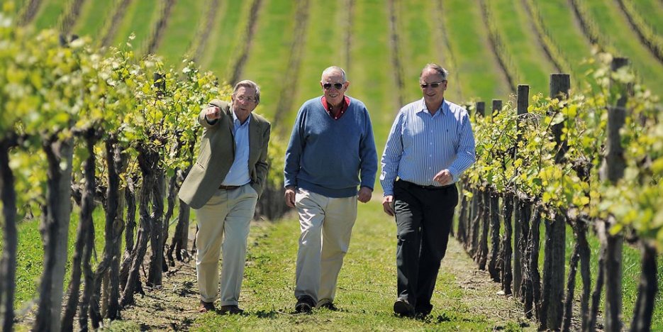Chris Hancock, Bob Oatley (founder, died in 2016), and Sandy Oatley his son, walk side by side up a wide avenue between rows of vines
