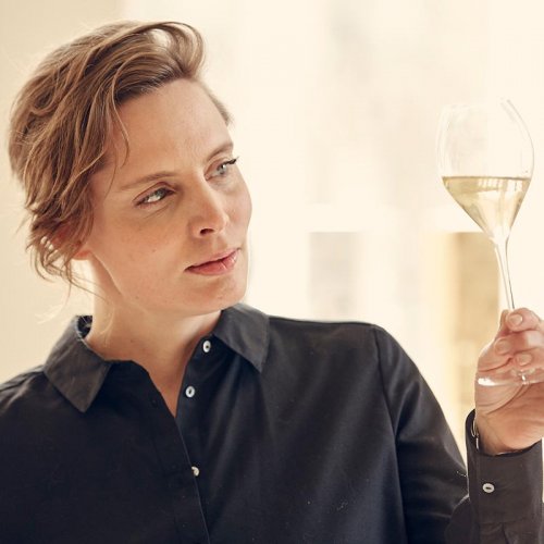 Vitalie Taittinger, Marketing and Communications Director examining a glass of Champagne in a sunlit room