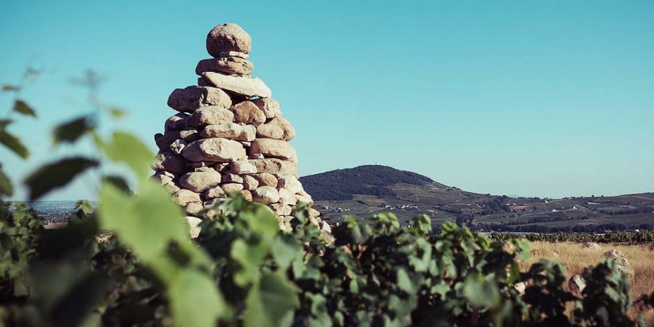 The 'Tour Boudon' - a large man made sandstone rock pile - adjacent to the Château de la Terrière vineyard, with Brouilly mountain in the background