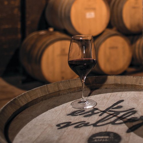 A glass of red wine sits on an Esk Valley branded barrel end in the cellar