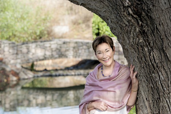 Eileen Crane, wearing a lilac shawl resting against a tree in the garden of the winery. Image credit Avis Mandel Pictures.