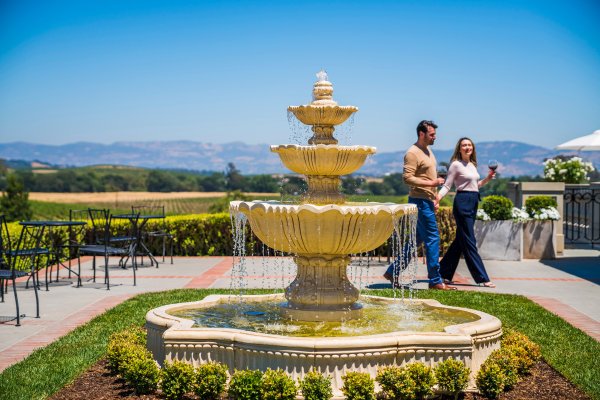 On the winery terrace, a couple walk behind the fountain