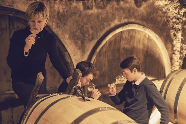 Catherine Corbeau-Mellot and sons check the aromas of a white wine sample pulled from the cask in the cellar