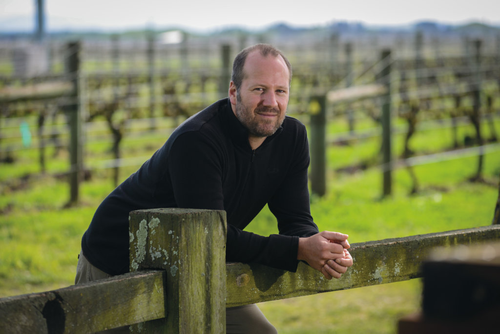 Richard Painter, Winemaker, leaning on a fence in the vineyard