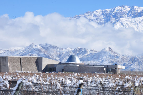 Valle de Uco Winery in a snowy vineyard, with the snow covered mountains behind