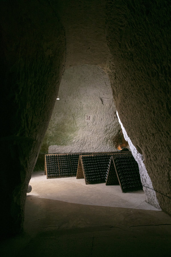 Peering through a carved split in the chalk of the Taittinger cellars at Champagne bottles in pupitres