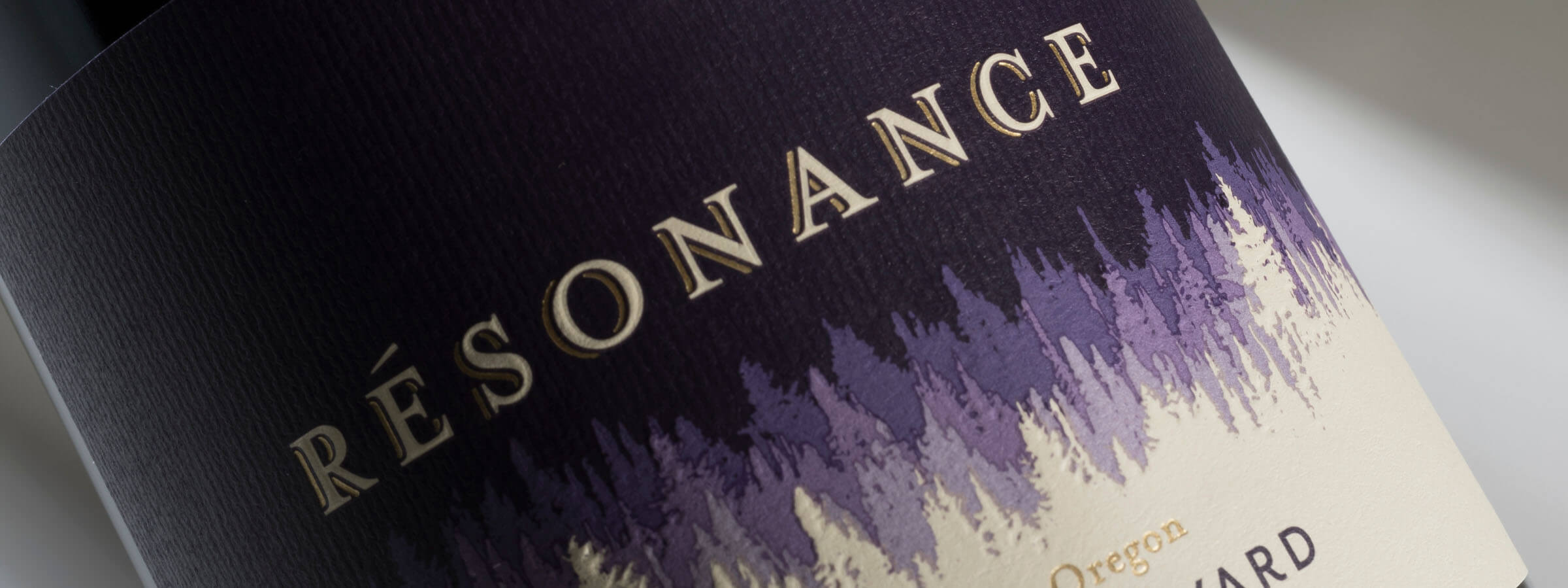 close up of RÉSONANCE name in cream on a deep purple colour wine label with graphic rows of trees beneath in shades of purple to cream beneath